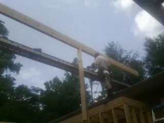 Carpenter setting a ridge beam over a new addition frame — Ice Dam Removal by Roofing Brothers in Mill Spring