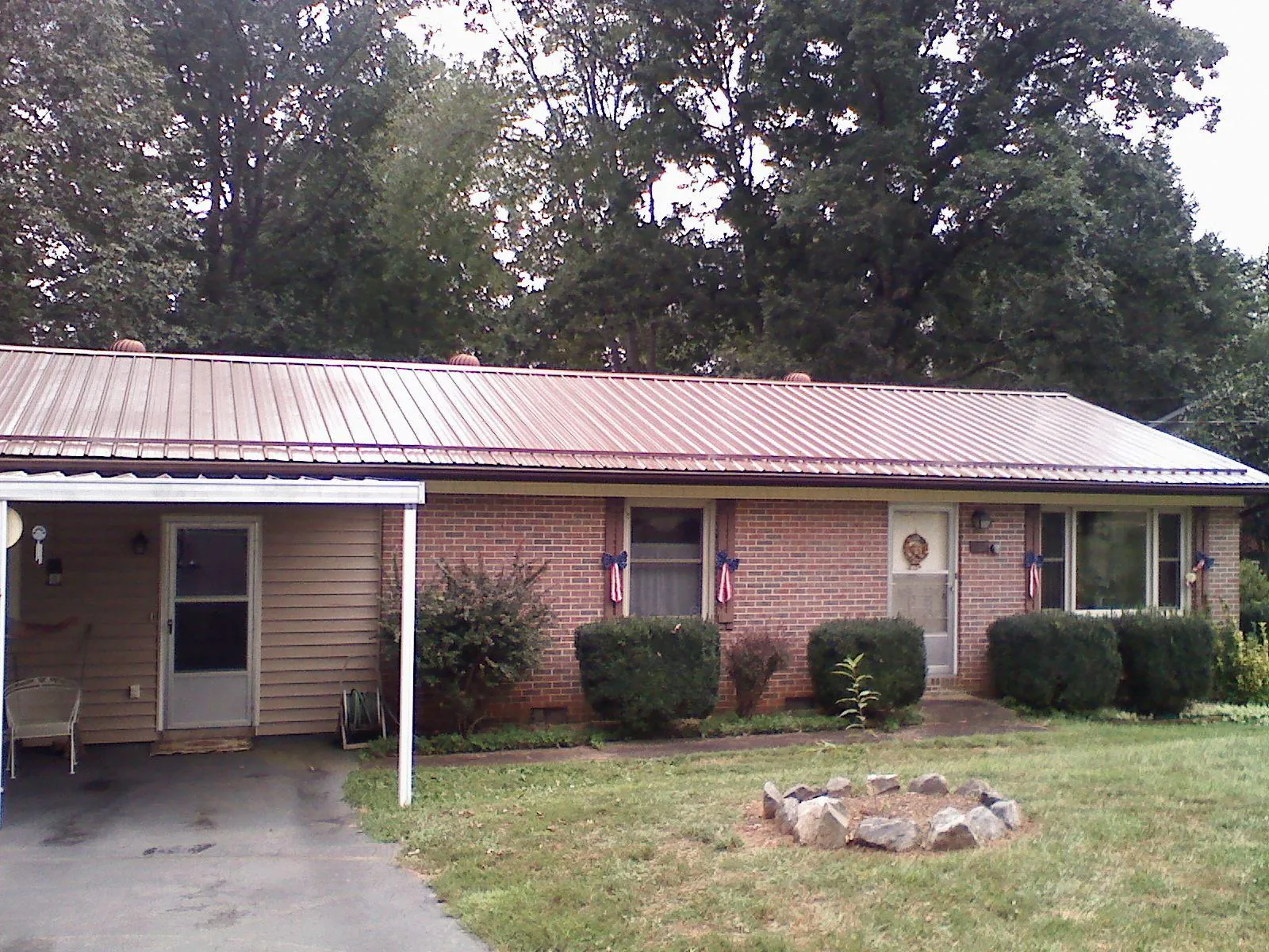 Bronze metal roof and carport on a brick ranch home — Roof Repair work by our crew in Mill Spring